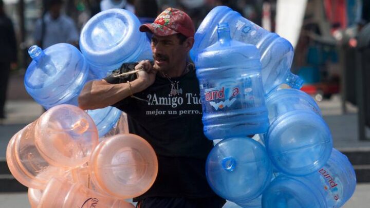 Señor mexicano cargando garrafones de agua